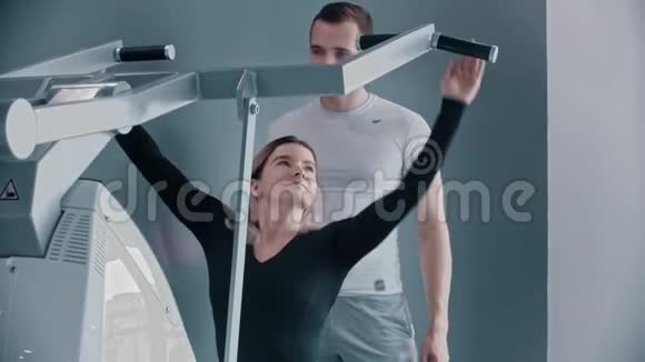与健身教练一起训练现代健身房一位年轻女子训练她的手视频的预览图