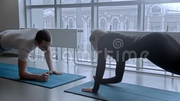 现代健身房男人和女人在健身房训练靠在瑜伽垫上的手视频的预览图