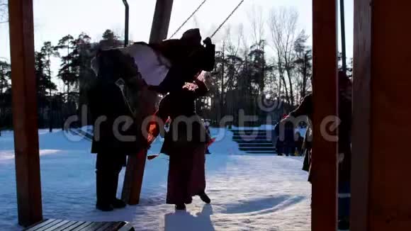 俄罗斯民间穿着传统服装的女人正在冬季公园里骑着秋千视频的预览图
