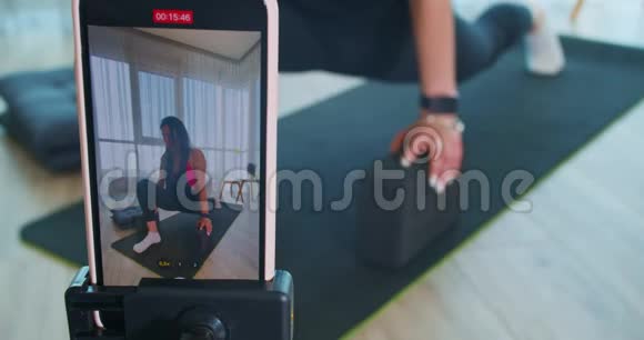 年轻女子正在伸展身体并在手机上录音在线课程4k视频的预览图