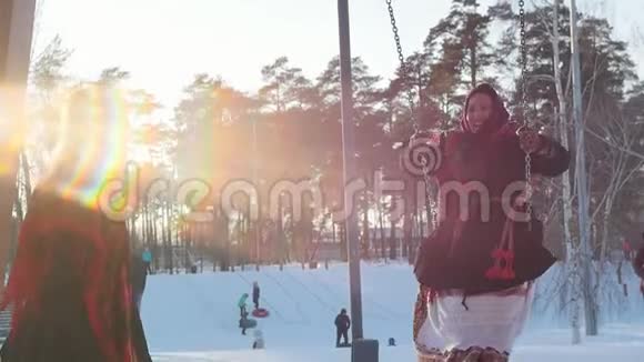 俄罗斯民间戴着鲜艳围巾的幸福女人骑在秋千上笑着视频的预览图
