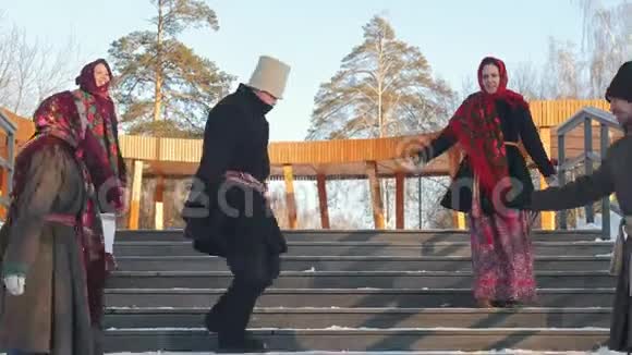 俄罗斯民间冬天穿着俄罗斯传统服装的男人和女人在楼梯上跳舞视频的预览图