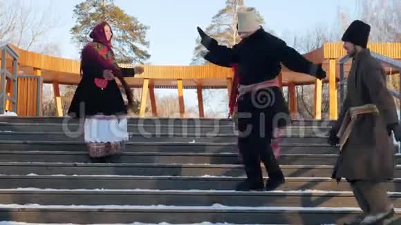俄罗斯民间男女穿着毛毡靴在公园的楼梯上跳舞视频的预览图