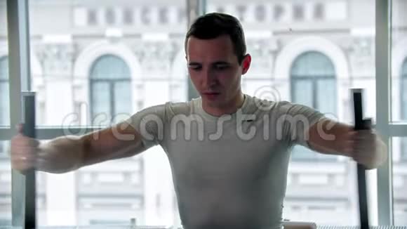 现代健身房一个年轻人在训练器械上做手臂运动视频的预览图