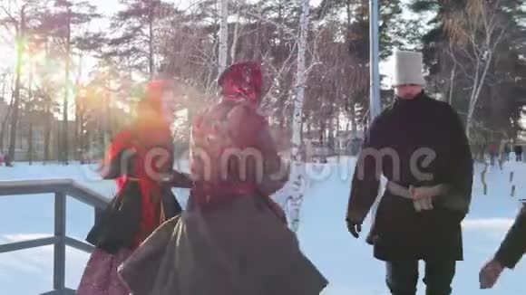 俄罗斯民间戴着鲜艳围巾的女人在阳光明媚的天气里和男人跳舞视频的预览图