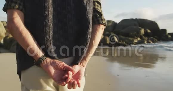 一位老人在海滩散步的后视图视频的预览图