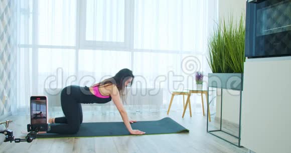 女人正在瑜伽垫上锻炼录制视频写博客4K视频的预览图