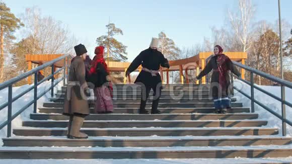 俄罗斯民间冬天穿着俄罗斯传统服装的人们在楼梯上跳舞视频的预览图