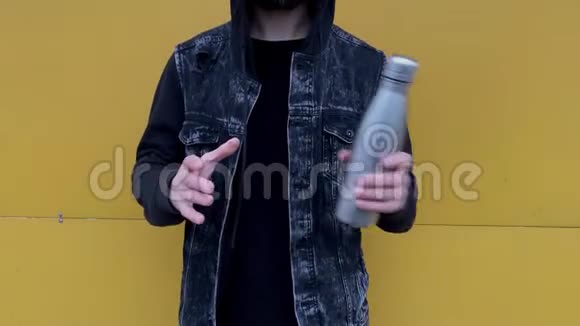 男性手抛出钢热瓶为水从手到手背景黄色视频的预览图