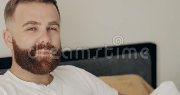 微笑的成年男子穿着休闲服装早上躺在床上的肖像近距离观看30多岁的帅哥视频的预览图