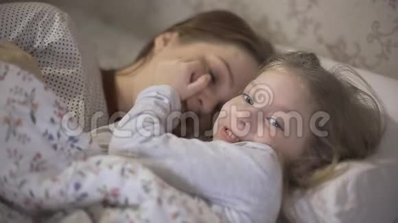 妈妈和小女儿睡觉后躺在床上互相拥抱父母之间的关系视频的预览图