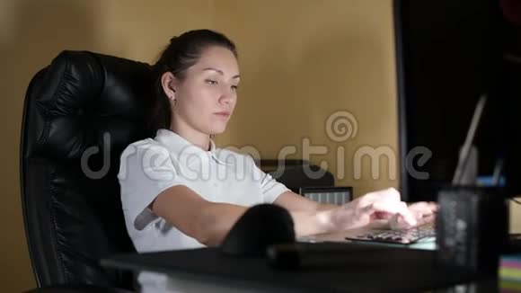 电脑上的一个疲惫的女孩坐在椅子上打哈欠视频的预览图