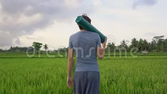 一个年轻人在一个美丽的稻田上进行瑜伽训练亚洲概念旅行视频的预览图