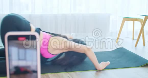 年轻女子正在录制一段视频在垫子上做瑜伽在线课程4K视频的预览图