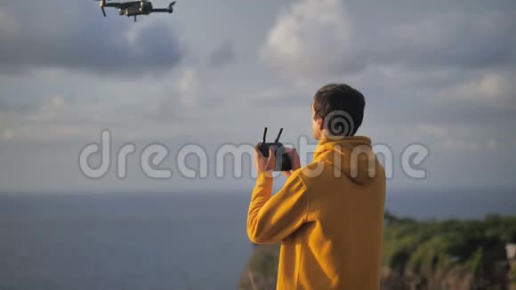 年轻的旅行者高高举起双手站在海洋上方的大山顶上在美丽的热带海滩上视频的预览图