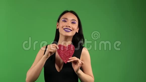 开朗的亚洲女孩手里拿着一颗心在孤独的背景下在情人节爱和快乐视频的预览图