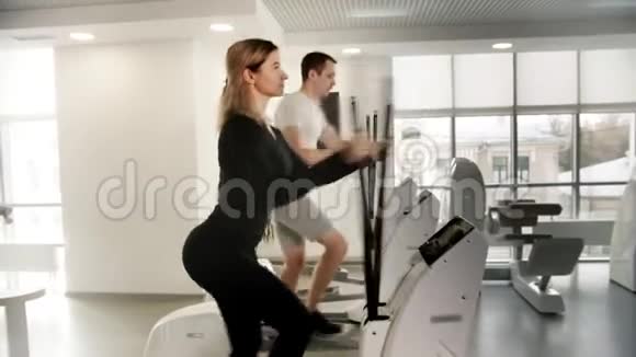 穿着运动服的年轻男女在现代健身房骑运动自行车锻炼腿视频的预览图