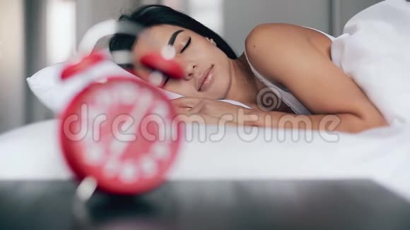 美丽的女孩睡在床上关掉闹钟继续睡觉视频的预览图