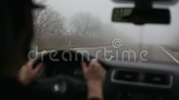 男司机在雾蒙蒙的路上开车从车内铺设现代道路视频的预览图