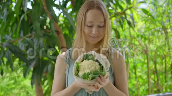 年轻女人把花椰菜放进一个可重复使用的袋子里减少塑料污染的概念减少和再利用视频的预览图