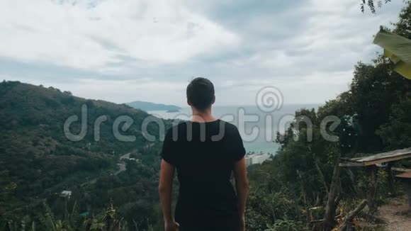 一位年轻的旅行者高高举起双手站在山顶上视频的预览图
