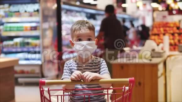 一个戴着面具的儿童在一辆购物车里等待着父母的到来那里的人视频的预览图