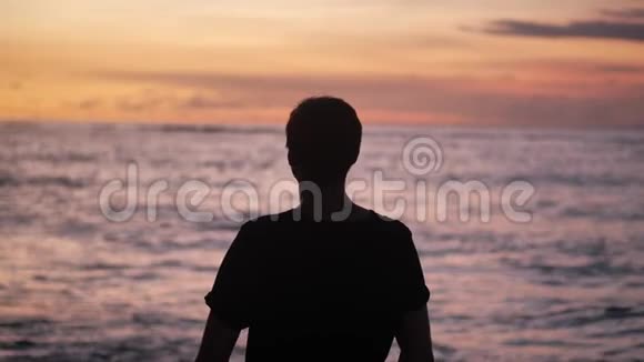 人类的剪影举起双手站在美丽的热带海滩上在红色的夕阳下自由概念视频的预览图