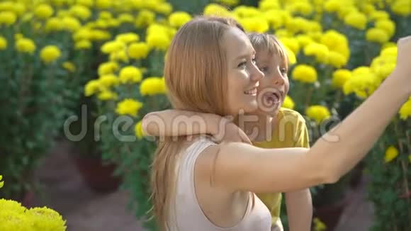 一位年轻的女士和她的儿子在许多黄色的花朵中自拍东亚人为了庆祝一个视频的预览图