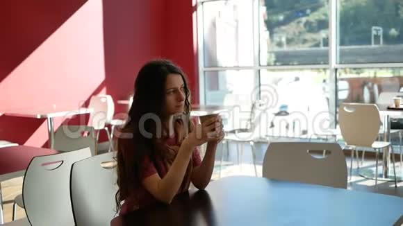 一个漂亮的女人独自坐在咖啡馆里喝着纸杯里的饮料视频的预览图