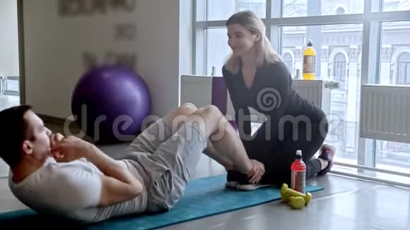 现代健身房微笑的男人和女人在健身房健身男人抽他的腹肌视频的预览图