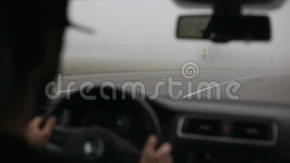 男司机在雾蒙蒙的路上开车从车内铺设现代道路视频的预览图