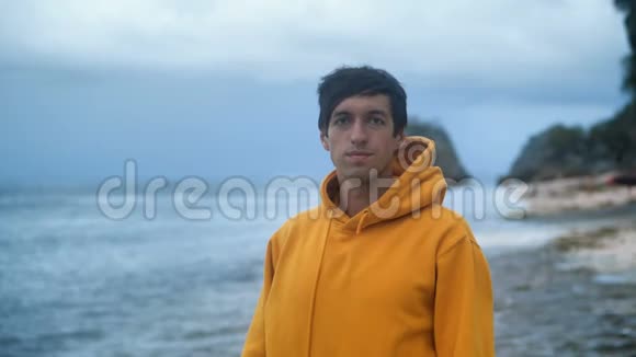 一位年轻的男性旅行者在雷雨前在一个野生热带海滩上的肖像视频的预览图