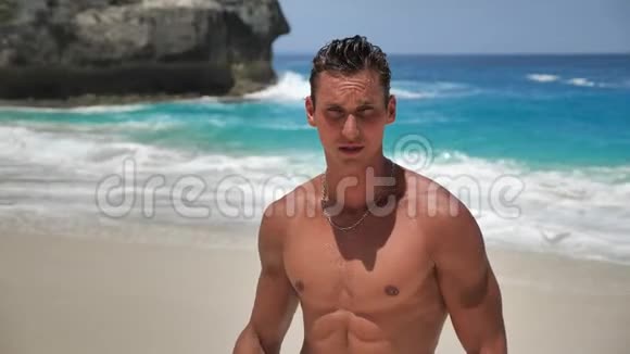 英俊的年轻人训练有素的肌肉运动员在美丽的海滩上摆姿势的肖像视频的预览图