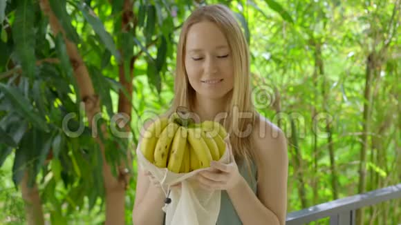 年轻的女人把香蕉放在一个可重复使用的袋子里减少塑料污染的概念减少和再利用视频的预览图