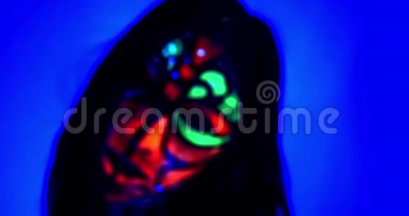 接近一个有紫外线身体艺术和绿色舌头的女人4k视频的预览图