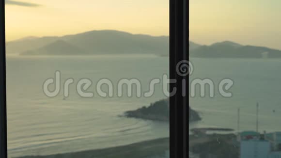 一位年轻女子在一间公寓里可以看到海岸和日出的全景她用智能手机站在旁边视频的预览图