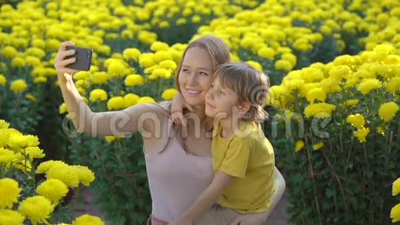 一位年轻的女士和她的儿子在许多黄色的花朵中自拍东亚人为了庆祝一个视频的预览图