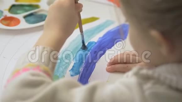 左手女孩用水彩颜料和画笔画彩虹孩子们的共同创造力视频的预览图