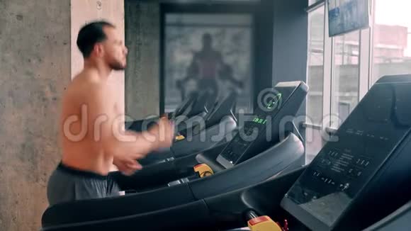 一个长着胡子有魅力的健美男子在跑步机上跑步视频的预览图