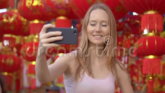 一个年轻的女人在许多东亚人用来庆祝农历的中国红灯笼中自拍视频的预览图