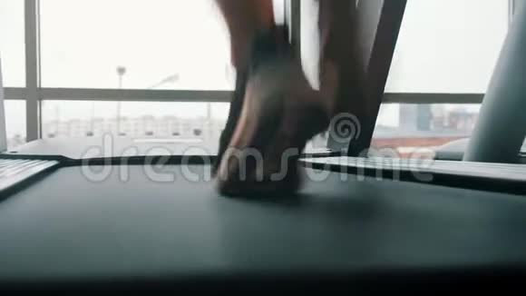 一个穿着运动鞋的在大窗户前的跑步机上跑步视频的预览图