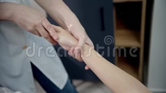 按摩按摩治疗师是揉捏一个女人的手在上面铺油视频的预览图