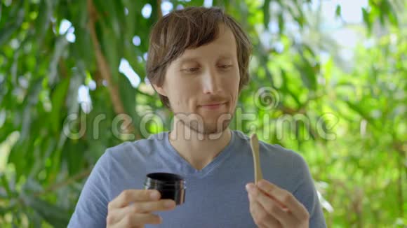 一个绿色环境中的年轻人用黑色活性炭粉刷牙用于牙齿美白他用的是视频的预览图
