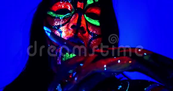 紫外线身体艺术和化妆在一个女人她的舌头上发光的油漆4K视频的预览图
