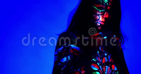 性感的女人有着耀眼的妆容和身体艺术摆在蓝色背景上4K视频的预览图