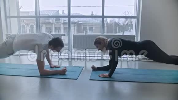 现代健身房男人和女人在健身房训练在瑜伽垫上拿着木板视频的预览图