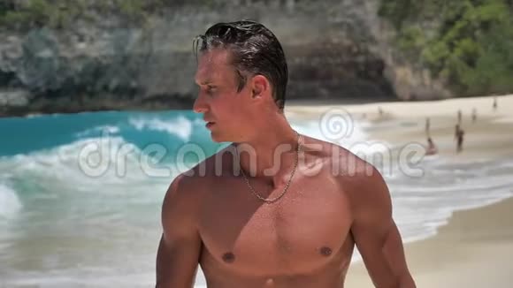 英俊的年轻人训练有素的肌肉运动员在美丽的海滩上摆姿势的肖像视频的预览图