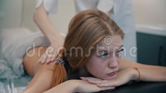 按摩年轻漂亮的女人在按摩时躺在沙发上视频的预览图