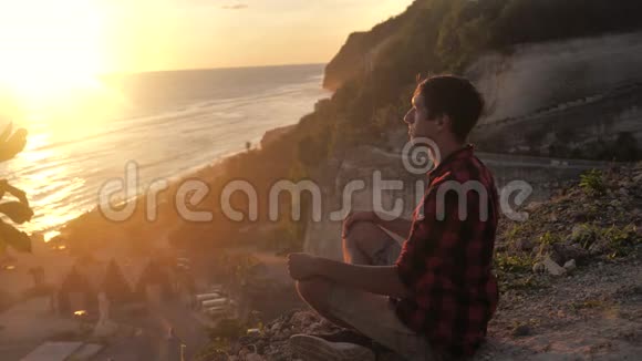 人们坐在岩石上对着美丽的日落沉思视频的预览图