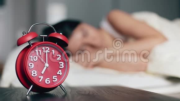 床头柜上的闹钟以熟睡的女人为背景视频的预览图